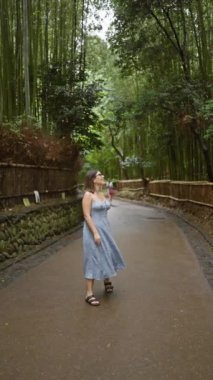 Gözlüklü güzel İspanyol kadın, Kyoto 'nun yemyeşil bambu ormanlarının arasında durup etrafa bakıyor, neşe ve şaşkınlık içinde..