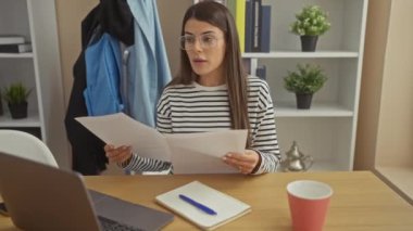 İspanyol kadın evdeki belgeleri okuyor. Laptop, defter, bitki dekorasyonu ve kahve fincanıyla..