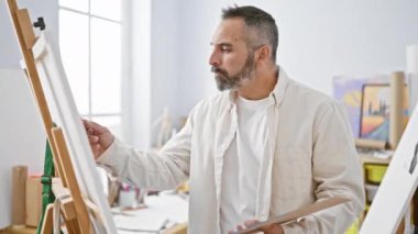 Parlak bir sanat stüdyosunda gri sakallı, yaratıcılık ve konsantrasyon tasvir eden olgun bir adam..