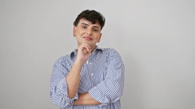 Olumlu düşünen, çizgili genç adam, ayakta duruyor, kameraya gülümsüyor kolları çapraz, elleri çenesinde, beyaz arka planda