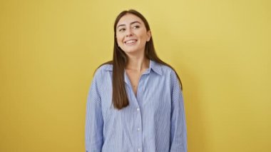 Young beautiful hispanic woman wearing shirt standing smiling with hands on chest with closed eyes and grateful gesture on face. health concept. over isolated yellow background