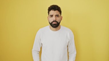 Kendine güvenen genç adam, sarı arka planda tek başına duran elleri ve parmaklarıyla italyan jestleri yapıyor.