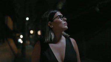Güzel, gözlüklü, sportif İspanyol kadın kendine güvenen, etrafa bakıp gülümseyen, Kyoto 'nun canlı sokaklarında gece ışıklarında sırılsıklam olan..
