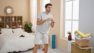 Genç adam rahat bir yatak odasında spor yapıyor. Spor aletleri ve modern dekorlarla.