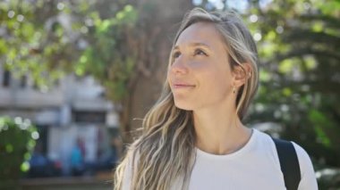 Sarışın kadın, güneşli parkta güneşlenirken gözlerini kapar..