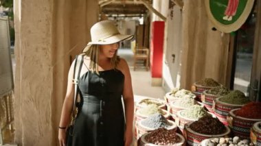 Güneş şapkalı gülümseyen bir kadın Dubai 'deki geleneksel bir çarşıda turizm ve kültürü somutlaştıran baharatları inceliyor..