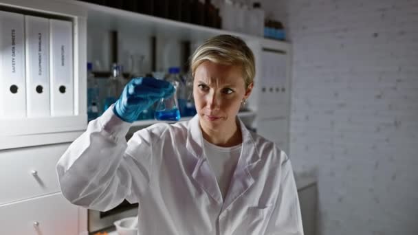 Skupiona Kobieta Naukowiec Bada Niebieską Substancję Chemiczną Kolbie Warunkach Laboratoryjnych — Wideo stockowe