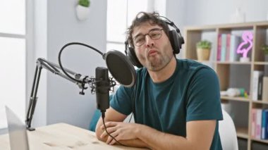 Radyo stüdyosundaki komik sahne! Yanaklarını şişiren genç bir İspanyol adam, kulaklıkla dinlerken ağzını havayla şişiriyor - gerçekten eğlenceli bir yüz.!