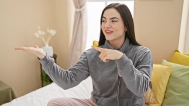 Pijamalı neşeli, genç İspanyol kadın şaşırmış, gösteriş yapıyor ve yatak odasından bir gülümseme sunuyor.