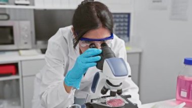 Neşeli bir İspanyol kadın bilim adamı laboratuvar ortamında mikroskopla çalışırken bir buluş kutluyor..
