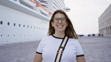 Deniz yolculuğu sırasında gemi güvertesinde gözlüklü gülümseyen bir kadın.