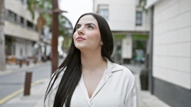 Beyaz gömlekli genç bir İspanyol kadın, kentin güzelliğini ve yaşam tarzını somutlaştıran bir caddede güven içinde duruyor..