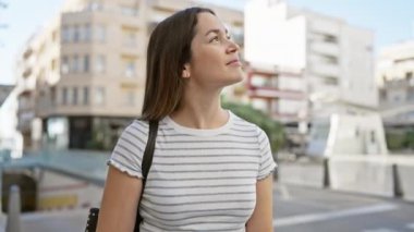 Şehir caddesinde, açık havada uzun kumral saçlı tefekkür eden genç bir kadın..