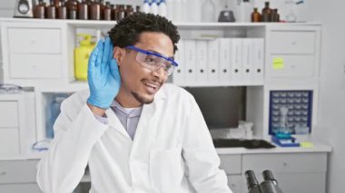 Sağırlık kavramı, mutlu Afrikalı Amerikalı bilim adamı, kulak kabartma, laboratuvar dedikodularını dinleme! Güvenlik gözlüğü takıyor, ilginç dedikodulara kulak kesiliyor..