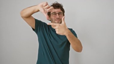 Gözlüklü, neşeli, genç, İspanyol bir adam. Elleriyle bir fotoğraf çerçevesi hazırlıyor. Basit beyaz arkaplana karşı yaratıcılık ve fotoğraf konsepti.