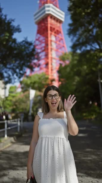 メガネクロッドの美しいヒスパニックの女性は 壮大な街並みの景色を望む有名な日本のランドマークである東京タワーで陽気な振りをする — ストック動画