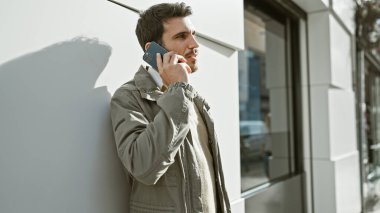 Yakışıklı, sakallı, güneşli şehir caddesinde telefonla konuşan bir İspanyol.