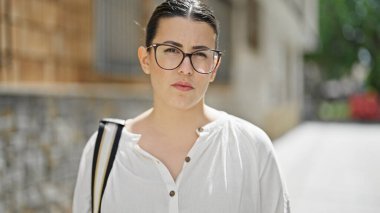 Sokakta ciddi bir ifadeyle duran genç, güzel İspanyol kadın.