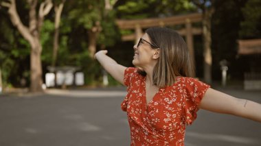 Neşeli İspanyol kadın kollarını açmış gülümsüyor, Meiji tapınağına bakıyor, kendine güvenini ve mutluluğunu gösteriyor.