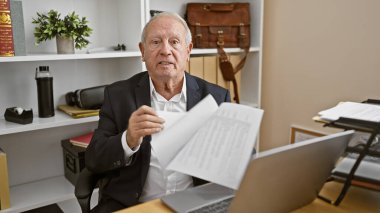 Ciddi, olgun, çalışkan, zarif, beyaz saçlı, tecrübeli bir iş adamı, ofiste ciddi bir şekilde konuşurken belgelere dalmış..