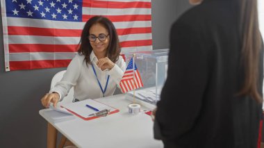 Amerikan Seçim Koleji 'nde bayrak arkaplanlı kadın seçmene yardım ediyor.