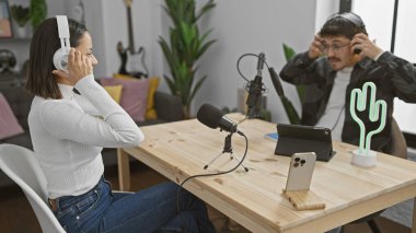 Podcast stüdyosunda kulaklık takan kadın ve erkek çevrimiçi yayına hazırlanıyor..