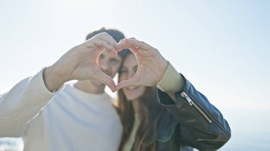 Bir çift, elleri ile bir kalp şekli oluşturur güneşli bir kumsal zeminine karşı, doğadaki aşkı ve birlikteliği sembolize eder..