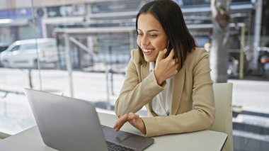 Modern ofis ortamında dizüstü bilgisayar kullanan gülümseyen kadın, üretkenliği ve çağdaş iş yaşamını resmediyor.