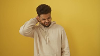 Kafası karışmış bir Afrikalı, sarı bir arka plana kafasını sürterek düşünceli bir ifadeyi canlandırıyor..