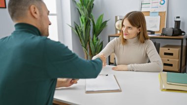 Modern bir ofiste profesyonel bir erkek ve kadın tokalaşması takım çalışmasını ve ortaklığı sembolize eder..