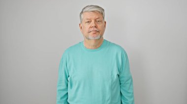 Gri saçlı bir adamın portresi. Sıradan giyinmiş beyaz bir arka planda kameraya bakıyor..