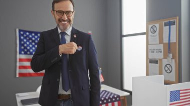 Middle-aged bearded man proudly showing 'i voted' sticker in american electoral college setting with flags clipart