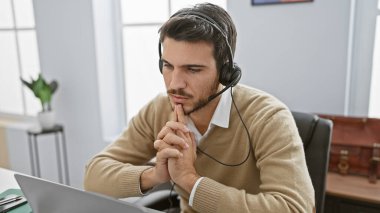 Ofis masasında sakallı, kulaklık takan düşünceli İspanyol bir adam..