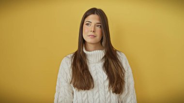 Beyaz kazaklı güzel bir İspanyol kadının portresi izole edilmiş sarı arka planda poz veriyor..