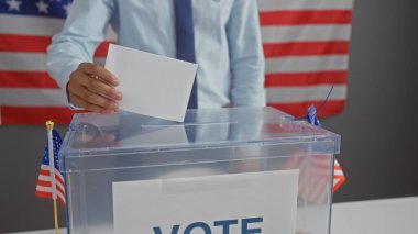 Amerikan seçimlerinde oy kullanan bir adam oy sandığı ve demokrasi ve vatandaşlığı temsil eden biz bayraklarla.