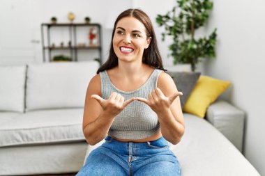 Genç ve güzel İspanyol kadın evdeki kanepede oturan sağırlarla iletişim kuruyor.