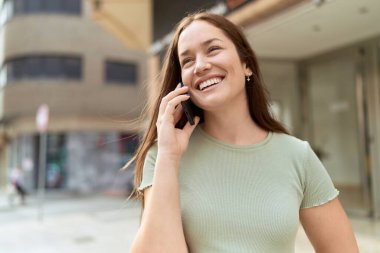 Genç, güzel bir kadın, gülümsüyor. Kendine güveniyor. Akıllı telefondan konuşuyor.