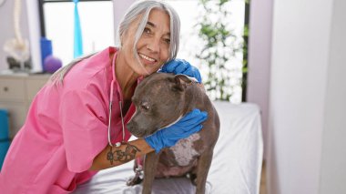 Kendine güvenen gülümseme, veteriner kliniğindeki hasta köpek yavrusunu ustalıkla muayene ederken orta yaşlı kadın veterineri canlandırıyor.