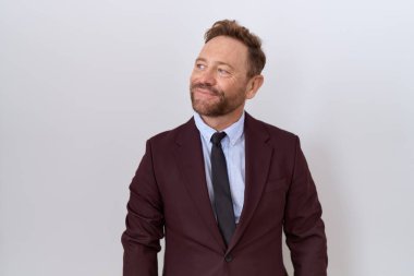 Orta yaşlı iş adamı, sakallı, kravatlı, takım elbiseli, gülümseyen, yan bakan ve düşünen.. 