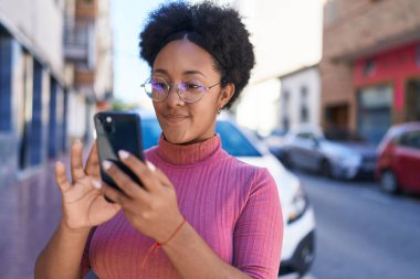 Afro-Amerikalı kadın sokakta akıllı telefon kullanarak kendine güveniyor.