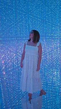 Gözlüklü güzel İspanyol kadın modern müzede fütüristik ışık sergisi açtı. Yaratıcılık ve mutluluğu ateşleyen bir sanat sergisi.