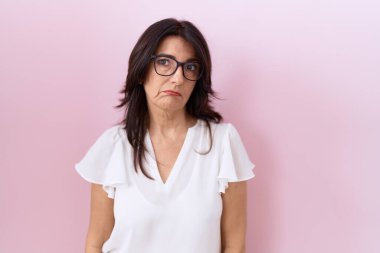 Orta yaşlı İspanyol kadın, günlük beyaz tişört ve gözlük takıyor. Bunalımda ve sıkıntıdan endişe ediyor. Kızgın ve korkmuş. hüzünlü ifade. 