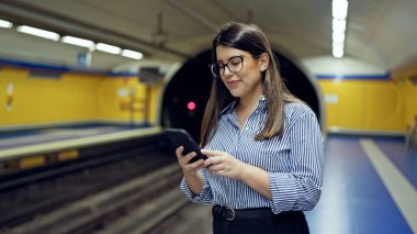 Madrid metro istasyonunda akıllı telefon kullanan güzel İspanyol bir kadın metroda bekliyor.