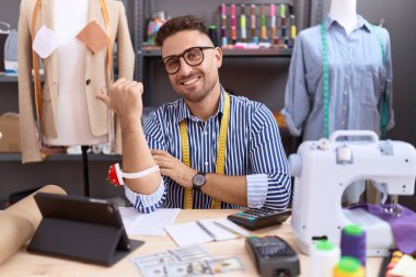 Sakal terzisi olan İspanyol bir adam atölyede çalışıyor. Gülümsüyor, gülümsüyor ve başparmağıyla işaret ediyor.. 