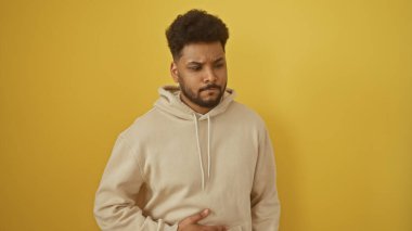 Kederli bir Afrikalı Amerikalı 'nın portresi. Karnı ağrıyan bir Amerikalı. Sarı arka planda izole edilmiş.