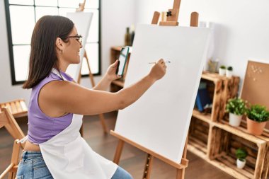 Sanat stüdyosunda akıllı telefon çizimi yapan genç ve güzel bir İspanyol kadın sanatçı.