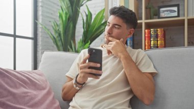 Yakışıklı İspanyol bir adam akıllı telefonu kapalı bir koltukta tutarken düşünür.