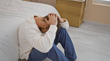 Stresli, genç İspanyol bir adam sabah endişesiyle boğulmuş, yatak odasında bir yatakta, yetişkin bir erkeğin evdeki yaşam tarzındaki duygusal acı ve depresyon portresi..