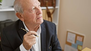 Ciddi ve odaklanmış son sınıf öğrencisi şüpheci, iş yerinde çalışan olgun bir işçinin kapalı bir portresi, elinde kalem, iş düşüncesine dalmış, özgüven ve başarı yayıyor..