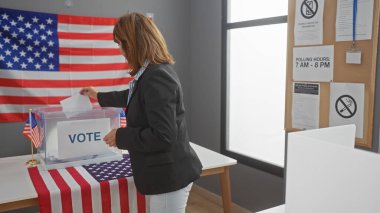 Amerikan seçim kabininde oy veren olgun bir kadın. Arka planda Amerikan bayrağı var.